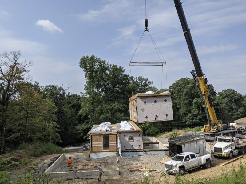 Crane setting modular home section onto poured concrete foundation