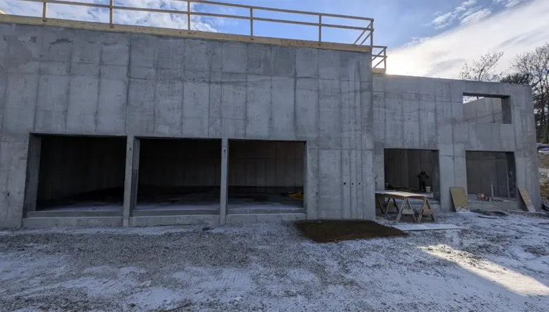 Finished poured concrete structure with garage bay openings in winter